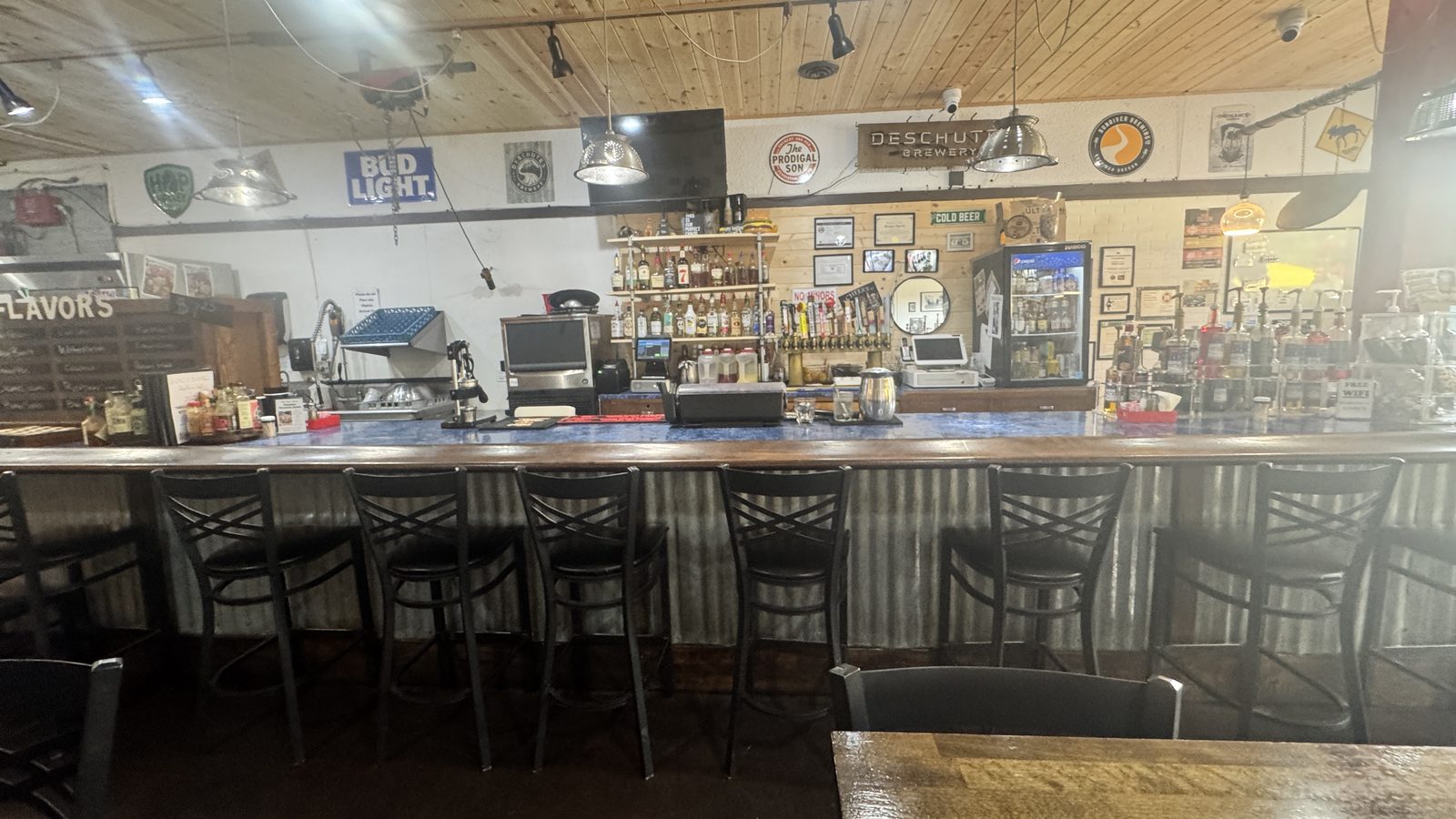 The bar at Broken Barrel: corrugated metal front, taps, and the back bar under wood ceiling