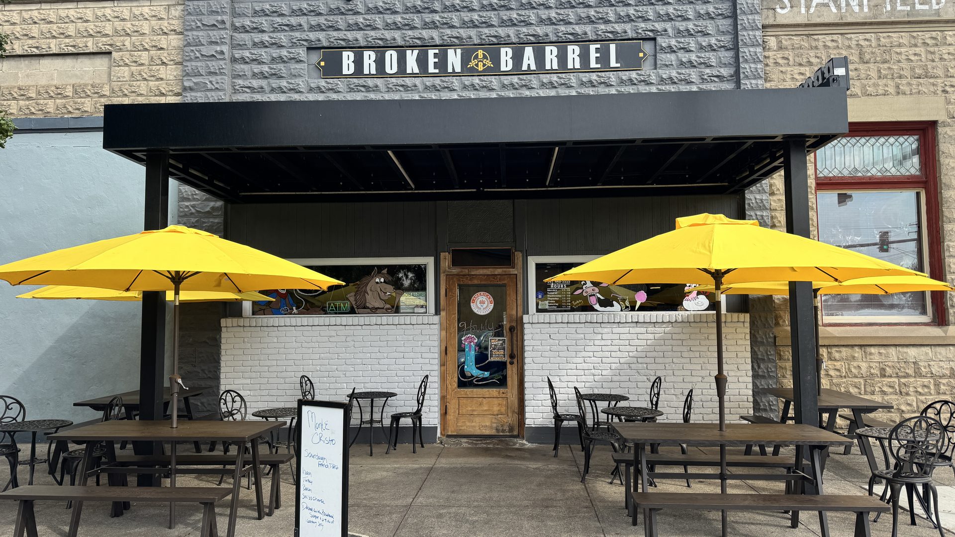 The Broken Barrel storefront on Coe Avenue in Stanfield, with the black awning and yellow patio umbrellas
