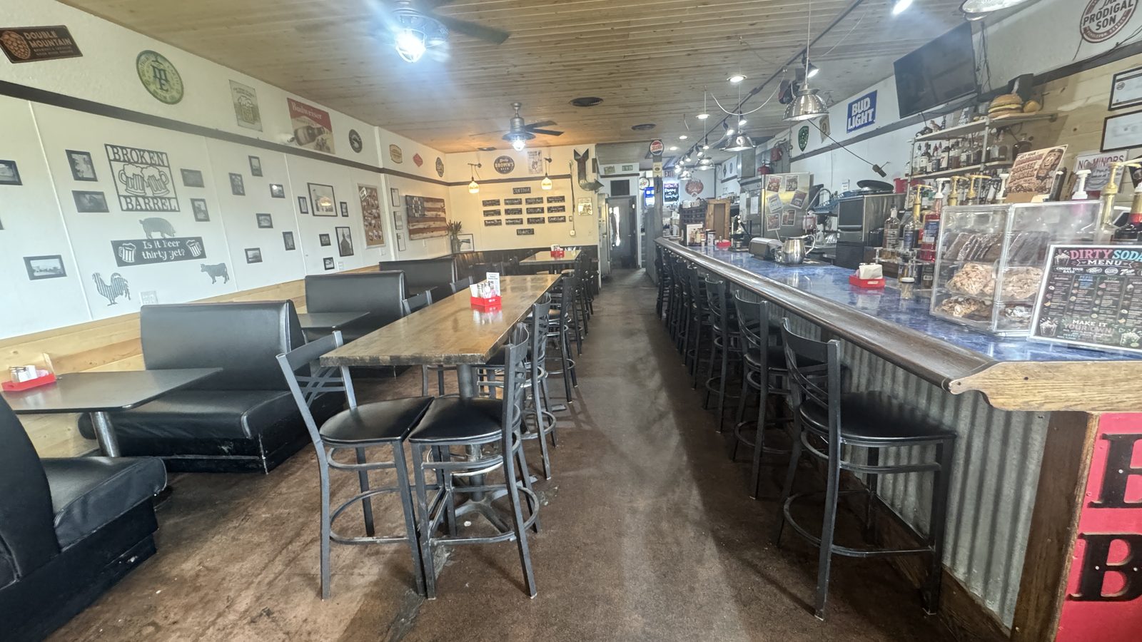 The long dining room at Broken Barrel with booths, high-tops and the corrugated metal bar